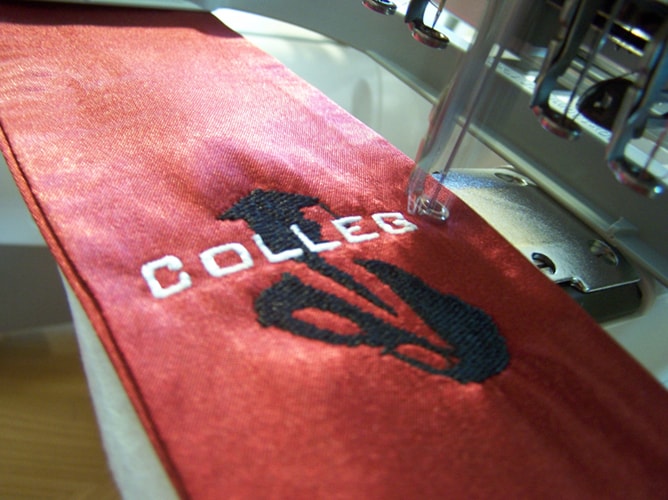 Stickmaschine bestickt eine College Fashion Schärpe mit Logo