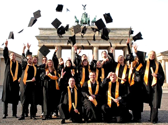 Absolventen werfen Doktorhüte am Brandenburger Tor in Berlin