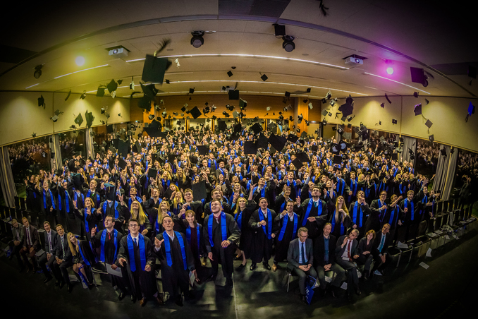 Absolventenfeier – Doktorhüte fliegen in die Luft, feierlicher Moment
